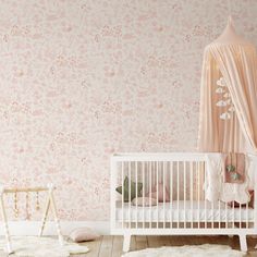 a baby's room with pink floral wallpaper and a white crib in the foreground