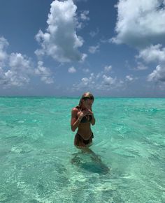 a woman standing in the ocean with her hat on