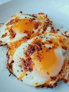 two fried eggs on top of rice in a white plate with mustard and seasoning