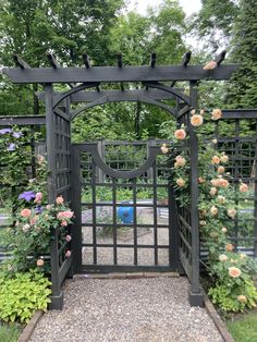 an open gate with flowers growing around it