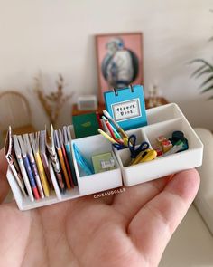 a hand holding a container filled with office supplies