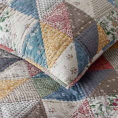 a close up view of a quilted pillow with many colors and patterns on it