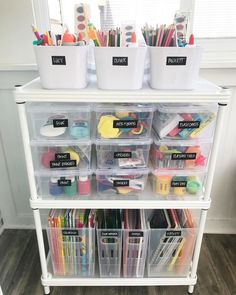 a white shelf filled with lots of plastic containers and bins full of art supplies