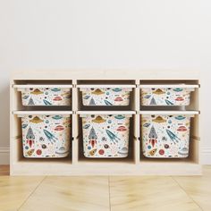 four storage bins with different designs on them in front of a white wall and wooden floor