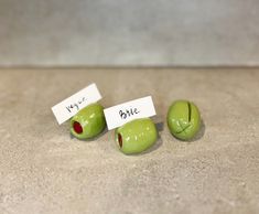 three green apples with faces and words on them sitting next to each other in front of a white piece of paper