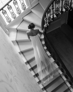 a woman in a white dress is walking down the stairs with her back to the camera