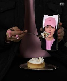 a woman taking a photo of herself eating cake with her cell phone in front of her