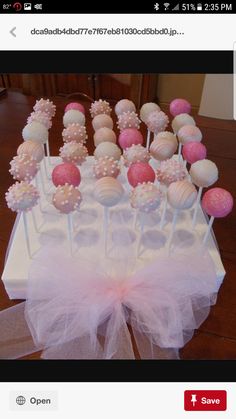 cake pops are arranged on a table with tulle bow around the edges, and pink and white frosting