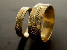 two gold wedding rings sitting on top of a black table with the words love written on them