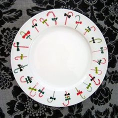 a white plate with candy canes on it sitting on a black floral tablecloth