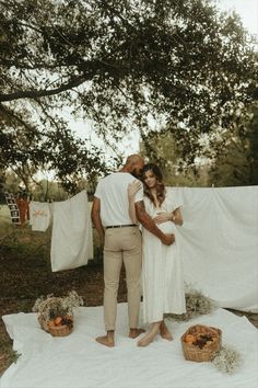 a man and woman standing next to each other on a blanket