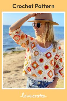 a woman standing on top of a beach next to the ocean wearing a hat and sunglasses