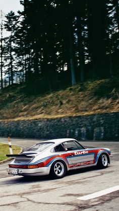 a car driving on a race track with trees in the background