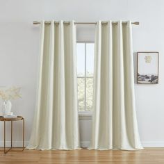 a living room with white curtains and wood floors