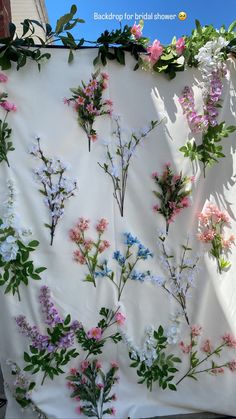 flowers are arranged on a white sheet with green stems and pink, blue, purple, and white flowers