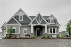 a gray and white house with lots of windows on the side of it's front door