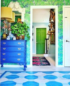 a blue dresser sitting next to a green door in a room with wallpaper on the walls