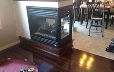 a fire place sitting on top of a hard wood floor next to a dining room table