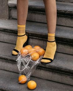 a person standing on some steps with oranges in their hand and one is wearing yellow socks