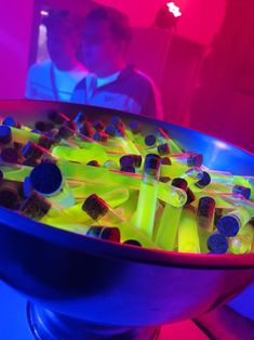 a bowl filled with lots of yellow and blue plastic bottles on top of a table