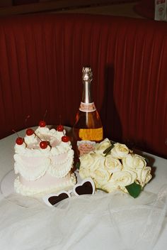 a table topped with a cake next to a bottle of wine and sunglasses on top of it