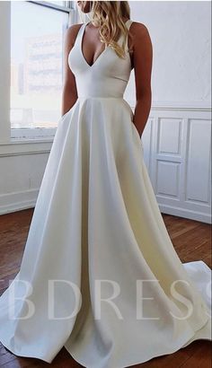 a woman standing in front of a window wearing a white dress