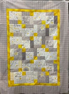 a yellow and gray quilt hanging on a wall