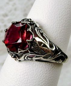 Simulated Red Ruby Ring (Matching Band also available) Daisy Design#66 Custom Made to Order This lovely Victorian reproduction filigree ring is lovingly hand crafted in sterling silver. This gorgeous ring is set with a flawless simulated red ruby.  The round full cut dazzling gem is 8mm (5/16") in diameter. The ring measures 12mm North South on the finger. The inside of the band is marked 925 for sterling. There is a small daisy on the sides of the gemstone. The delicate filigree travels around Daisy Crown, Ring Matching, Daisy Design, Red Band, Antique Design, Filigree Ring, Matching Band, Red Ruby, Engraved Items