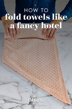 a person is holding an old towel on top of a table with the words how to fold towels like a fancy hotel