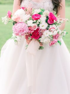 a bride holding a bouquet of pink and white flowers