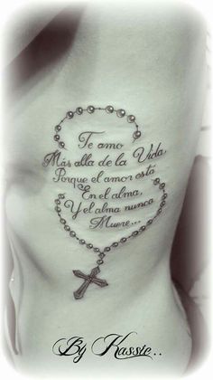 the back of a woman's stomach with a rosary and cross tattoo on it