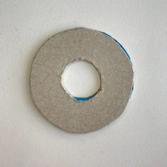 a white wall with a hole in the middle that has blue tape on it and there is a piece of felt inside