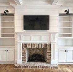 a living room with white bookcases and a tv mounted on the wall above a fireplace