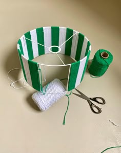 a green and white striped piece of fabric next to yarn, scissors and twine