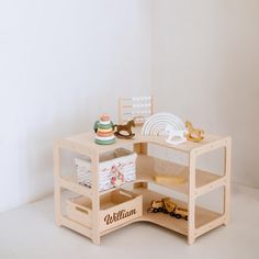 a wooden toy table with toys and other items on it's shelf, sitting against a white wall