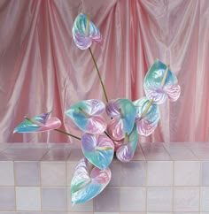 a vase filled with flowers sitting on top of a tiled counter next to a pink curtain