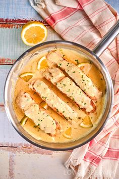 a pan filled with chicken covered in sauce and garnished with lemon slices