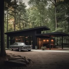 a black car is parked in front of a house surrounded by tall trees and greenery