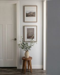 there is a vase with some flowers on the table in front of the door and pictures on the wall