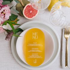 a plate with some grapefruit on it next to a fork and glassware