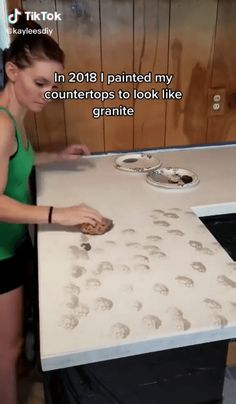 a woman in a green top is painting a table