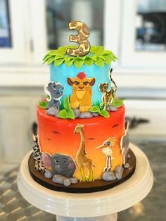 a multi - tiered birthday cake decorated with animals and the number three on top