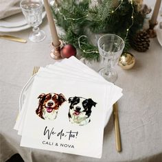 two dogs on napkins sitting on top of a table next to glasses and candles