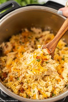 someone is stirring some pasta into the pot with a wooden spoon in it and there are vegetables on the side