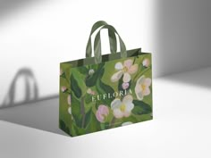 a shopping bag with an image of flowers painted on the front and side, sitting on a white surface