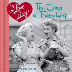 two women laugh together in front of a heart - shaped sign that says love lucy the toys of friendship