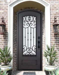 the front door to a house with potted plants on either side and an iron gate