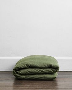 a green pillow sitting on top of a wooden floor next to a white wall and wood floor