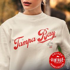 This Tampa Bay Buccaneers Crewneck Sweatshirt would make the perfect gift for your diehard Tampa Bay football fan.  This vintage collection features a Tampa Bay retro style typography design and team colors USA flag.  Perfect birthday, Christmas or anytime gift for the hardcore Tampa Bay football fan in your life! Ideal for any situation, a unisex heavy blend crewneck sweatshirt is pure comfort. These garments are made from polyester and cotton. This combination helps designs come out looking fresh and beautiful. The collar is ribbed knit, so it retains its shape even after washing. * 50% cotton, 50% polyester * Medium-heavy fabric (8.0 oz/yd² (271.25 g/m²) * Loose fit * Sewn-in label * Runs true to size * Tear away label * Color of products may appear different on various monitors * Machi Crew Neck Tops With Lettering For Fan Gear, Crew Neck Tops With Lettering For Fans, Fan Merchandise Tops With Lettering, Fan Merchandise Lettering Tops, Football Sweatshirt, Tampa Bay Buccaneers, Retro Stil, Perfect Birthday, Usa Flag