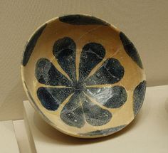 a black and white bowl with flowers on the inside is sitting on a table next to a cup